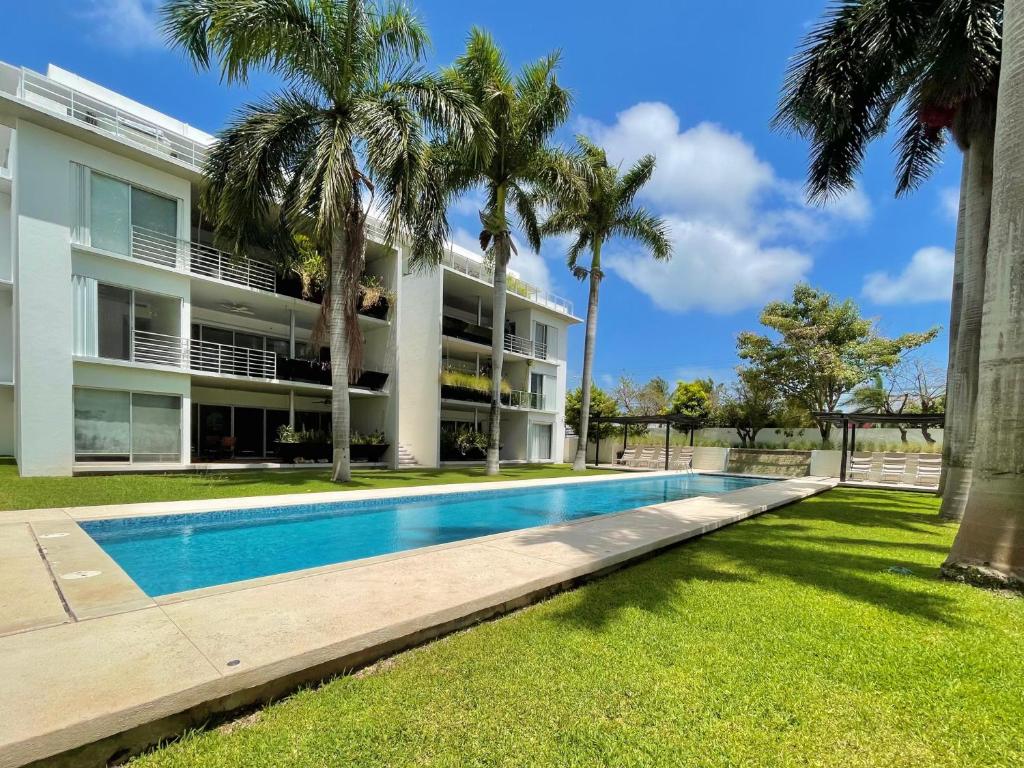 un edificio de apartamentos con piscina y palmeras en Bonampak by Andiani Travel - Families or work stays only, en Cancún