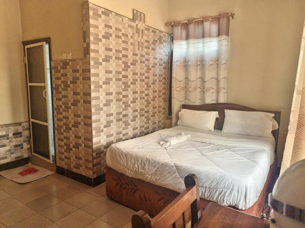 1 dormitorio con cama y pared de azulejos en Big mountain inn, en Moshi