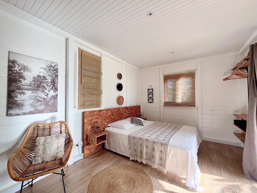 ein Schlafzimmer mit einem Bett und einem Stuhl darin in der Unterkunft Kaz et Palmiers in Saint-François
