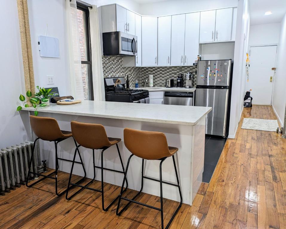 una cocina con un gran mostrador blanco y 3 taburetes en Lavish Downtown Manhattan Oasis in Union Square, en Nueva York