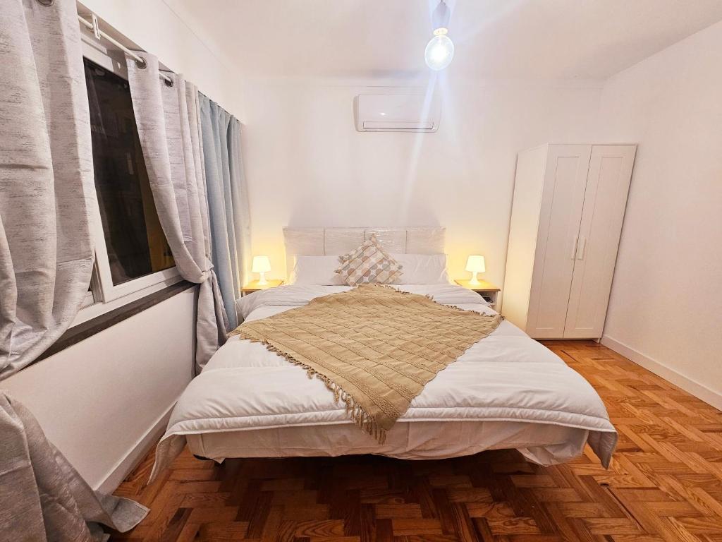 um quarto com uma cama com lençóis brancos e uma janela em Peers Guest House em Cascais