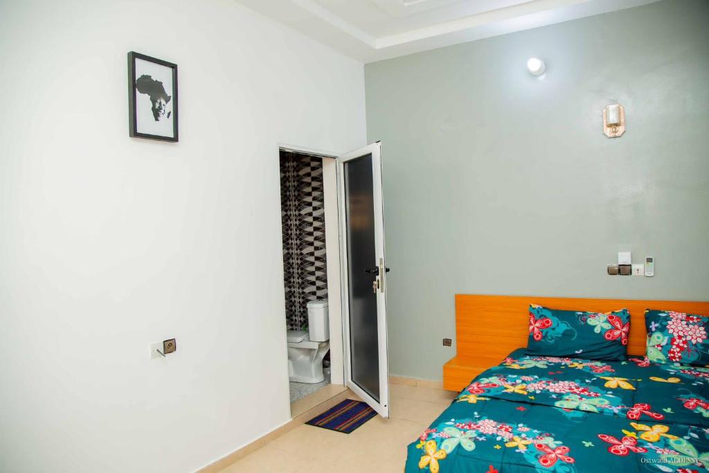 a bedroom with a bed and a door to a bathroom at Le Calypso in Cotonou