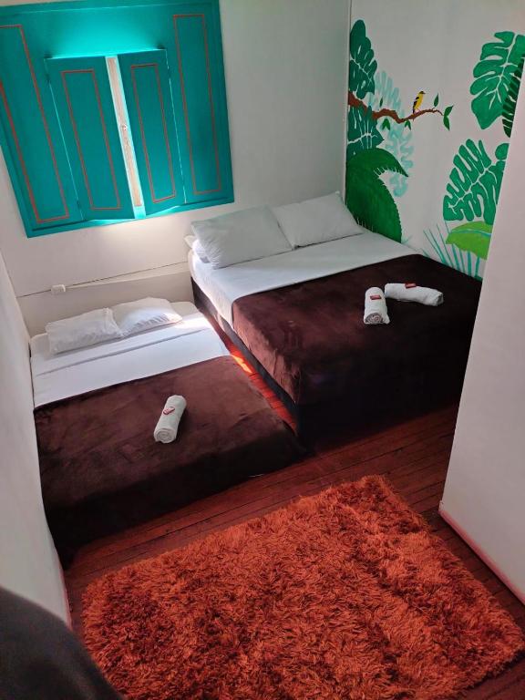 a bedroom with two beds and a red rug at Kimaná Hostal in Santa Rosa de Cabal