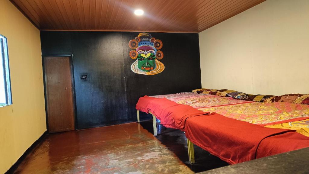 dwa łóżka w pokoju z maską na ścianie w obiekcie Triloka Dorm by The Offbeat Crew w mieście Munnar
