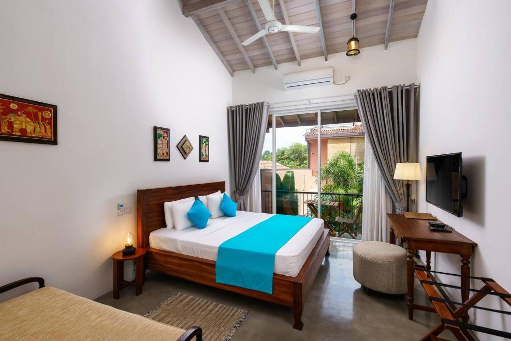 a bedroom with a bed and a desk and a window at Angam Suites Colombo in Sri Jayewardenepura Kotte