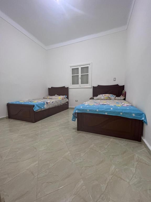 een kamer met 2 bedden in een kamer met een vloer bij فيلا الواحة للحفلات والمناسبات بالعجمي/أبو يوسف in Alexandrië
