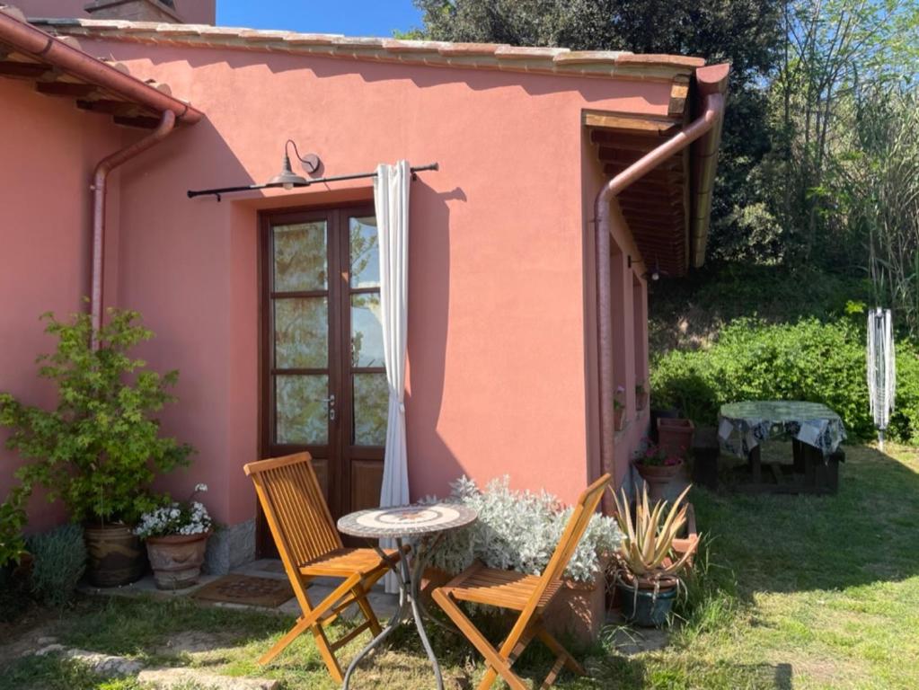einen Tisch und Stühle vor einem rosa Haus in der Unterkunft Casa Dell'Arte Botanica in Palaia