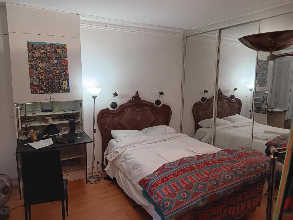 1 Schlafzimmer mit 2 Betten, einem Schreibtisch und einem Spiegel in der Unterkunft Apart calmo em paris jourdain in Paris