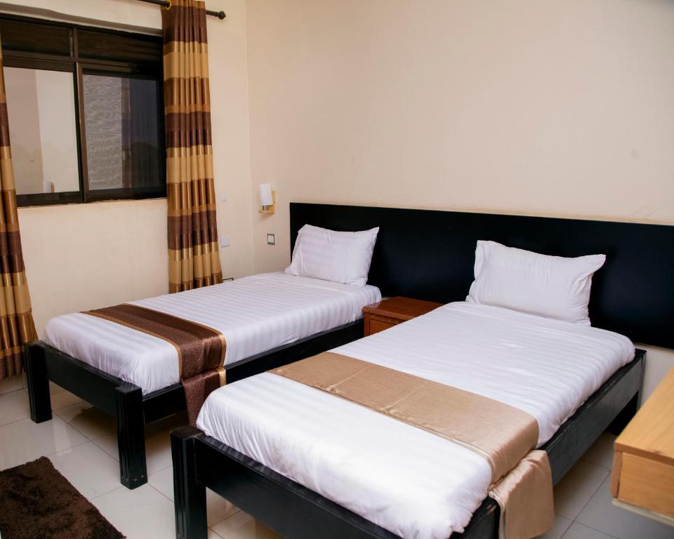 a room with two beds and a window at UBUNTU PALACE HOTEL - RUNATI in Kampala