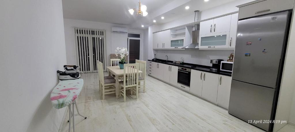 uma cozinha branca com uma mesa e um frigorífico em J&M Rooms em Shkodër