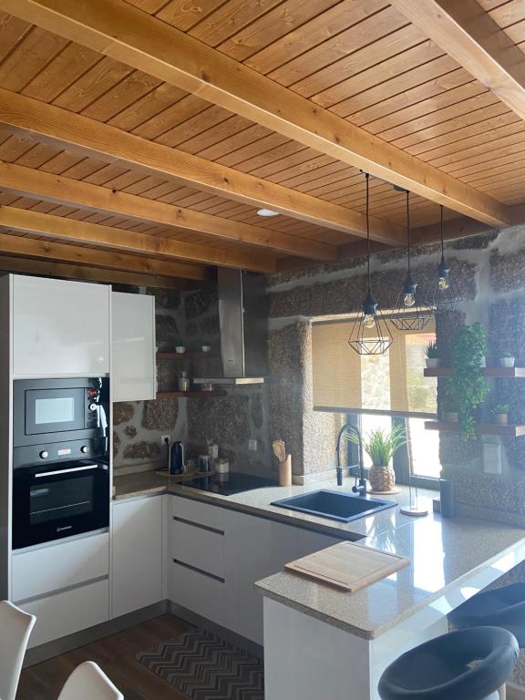 eine Küche mit weißen Geräten und einer Holzdecke in der Unterkunft Casa da Ti Mília in Trancoso
