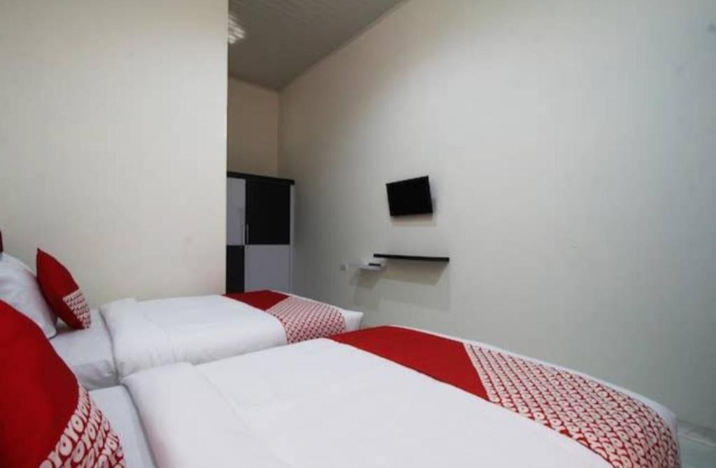 a room with two beds and a television in it at Wisma Alda in Kedaton