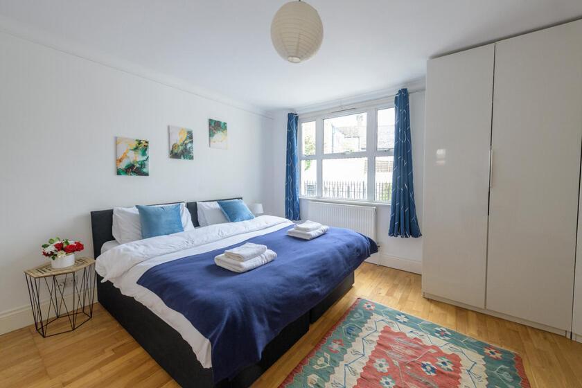 Spectacular 3 Bed in Blackheath في لندن: غرفة نوم بسرير كبير مع شراشف زرقاء ونافذة