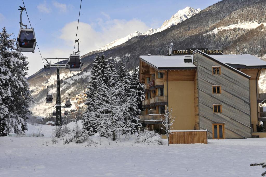 a ski lodge in the snow with a ski lift at Hotel Garni Pegrà in Ponte di Legno