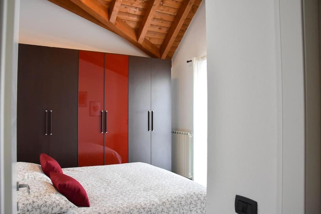 um quarto com uma almofada vermelha numa cama em CA' GIALLA 5 - sul Lago di Lugano, self check-in e parcheggio - em Cadegliano Viconago