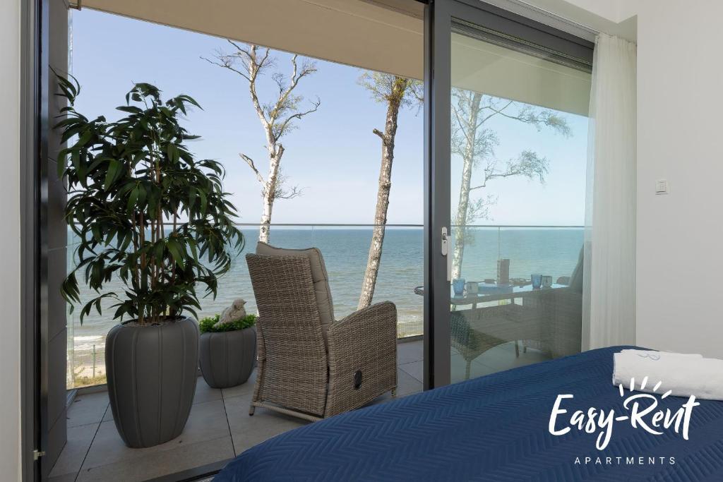 1 dormitorio con cama y vistas al océano en Double Blue Bien - Easy-Rent Apartments bezpośrednio przy plaży, en Rewal