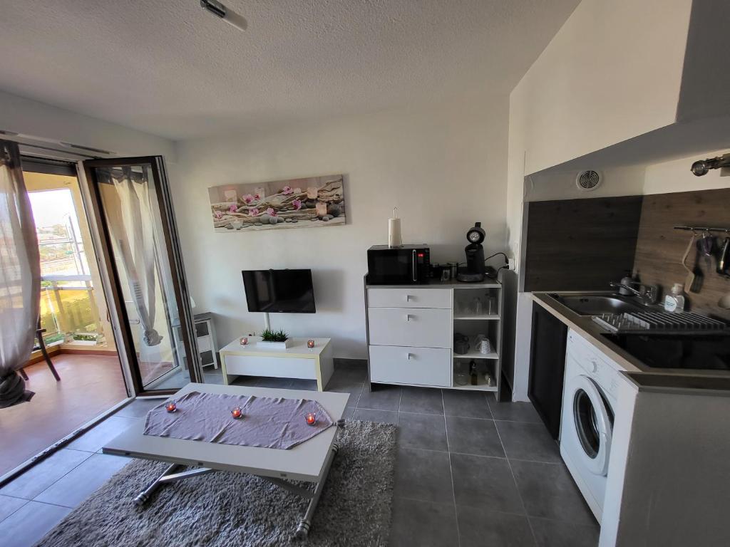 Il comprend une cuisine équipée d'une cuisinière, d'un évier et d'une table. dans l'établissement Studio confort, à Fréjus