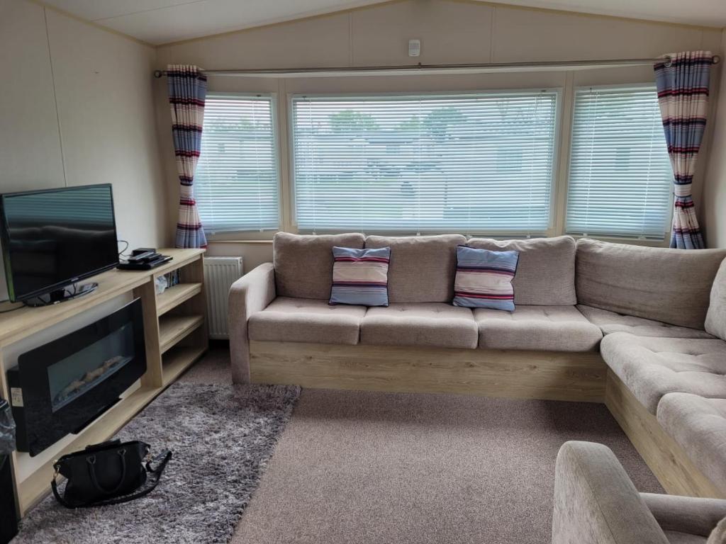a living room with a couch and a television at Highfield Grange Holiday Park in Little Clacton