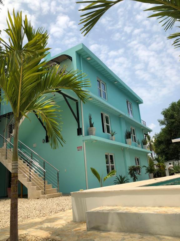 ein blaues Gebäude am Strand mit einer Palme in der Unterkunft CABAÑAS CRAZY COCONUTS in San Antero