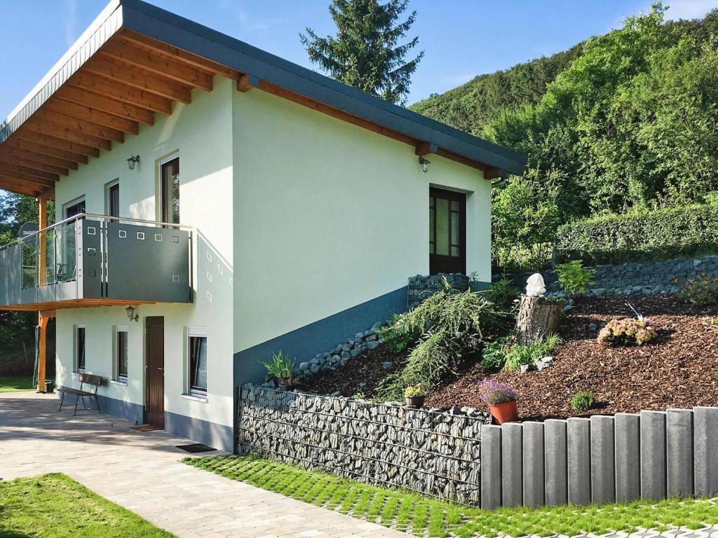 a white house with a stone retaining wall at Attraktives Ferienhaus mit Balkon in Kaltennordheim