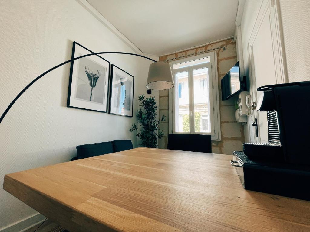 ein Esszimmer mit einem Holztisch und einem Fenster in der Unterkunft Respire Bordeaux in Bordeaux