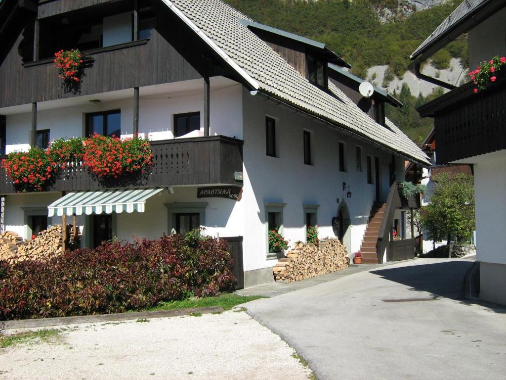 um edifício branco com caixas de flores nas varandas em Apartmaji Hodnik Stara Fužina em Bohinj