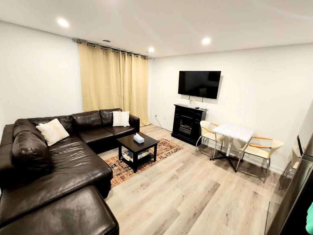 a living room with a leather couch and a television at Niagara Escape Crib: 3km from NiagaraFalls in Niagara Falls
