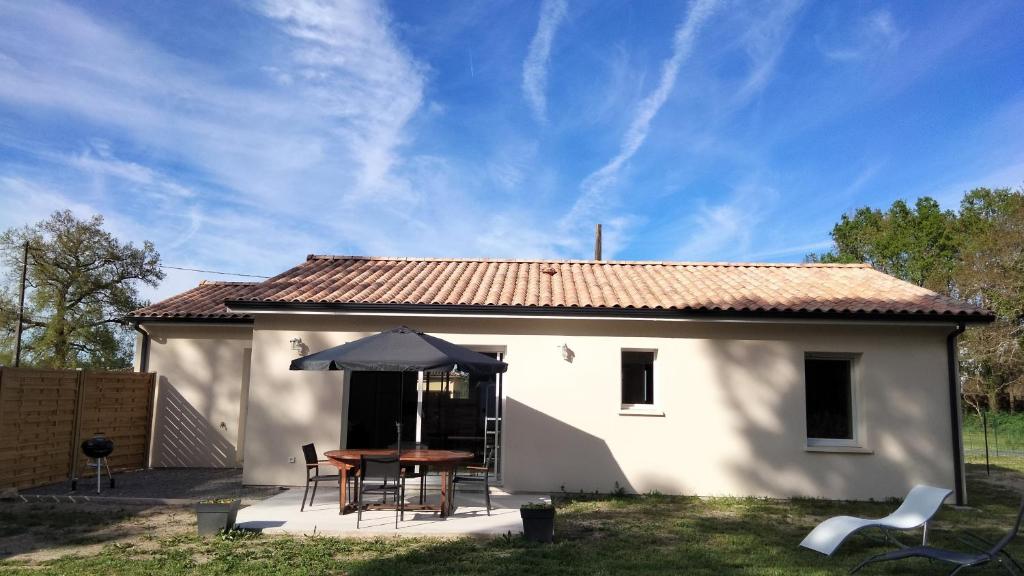 une petite maison blanche avec une table et un parasol dans l'établissement Gite du vieux chêne, à Reignac