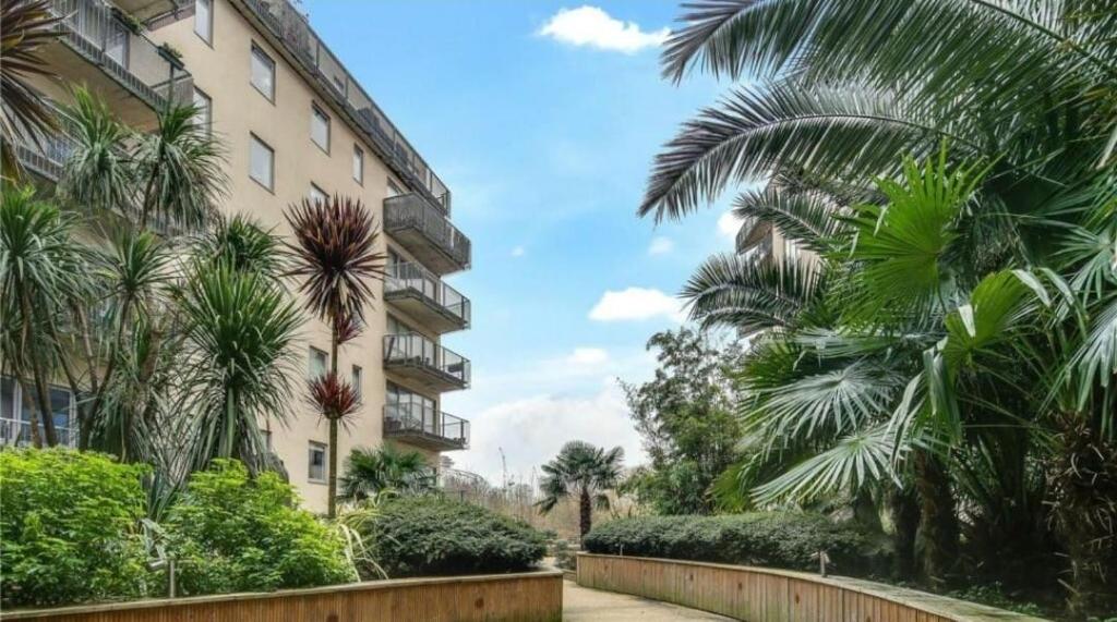 a building with palm trees in front of it at Riverside 2 Bed Apartment with Free Parking in London
