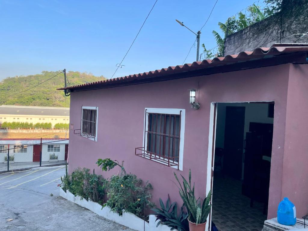 una casa rosa con una porta su una strada di Cozy Cabin in Santa Tecla, 25 mins from surf city a Nueva San Salvador