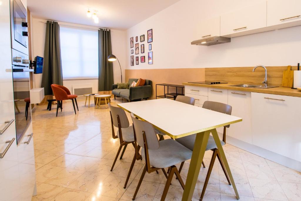 eine Küche und ein Wohnzimmer mit einem Tisch und Stühlen in der Unterkunft Hesdin Appart Holidays 1 in Hesdin