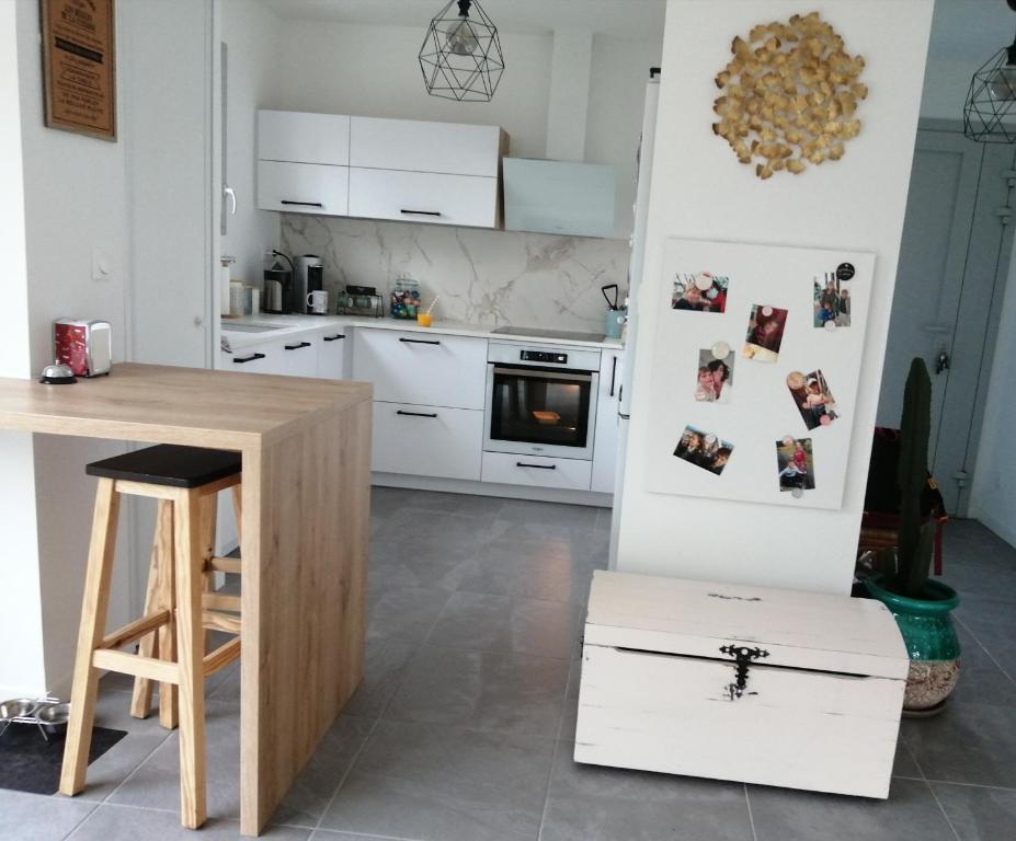 une cuisine avec des placards blancs et une table en bois dans l'établissement la maison du bonheur, à Anglet