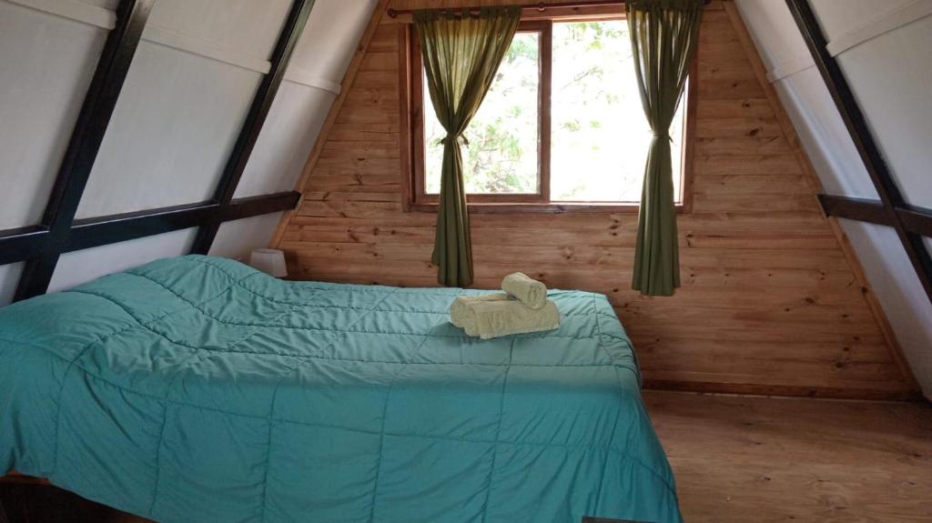 1 dormitorio con 1 cama verde en una cabaña de madera en La Alpina en Panaholma
