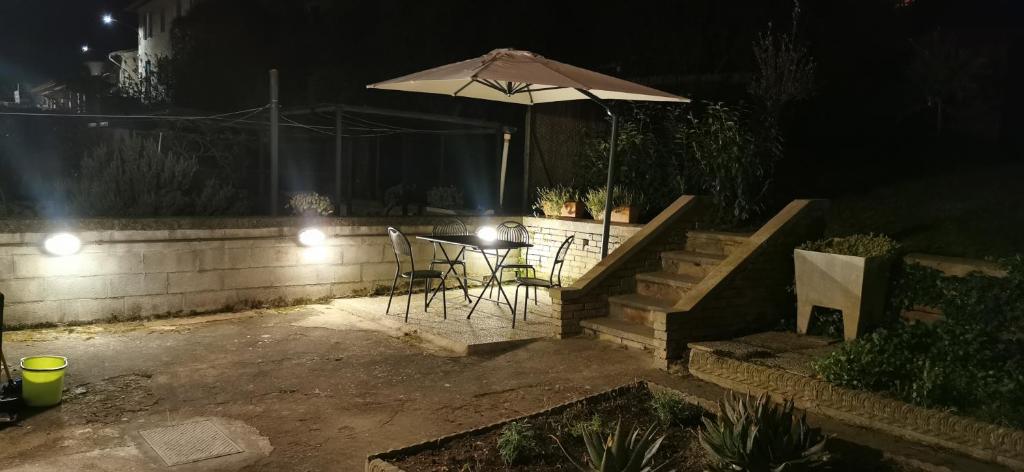 a patio with a table and an umbrella at night at EM Apartment in Siena
