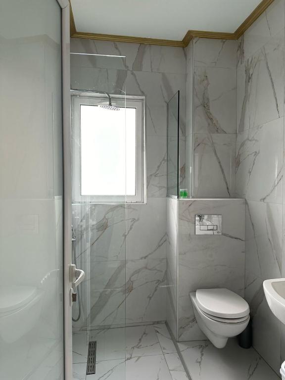 a bathroom with a shower and a toilet and a sink at Summer Gate Hotel in Ksamil