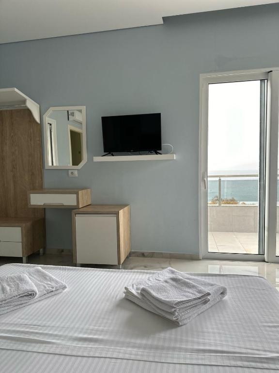 a white bedroom with a bed and a television at Summer Gate Hotel in Ksamil