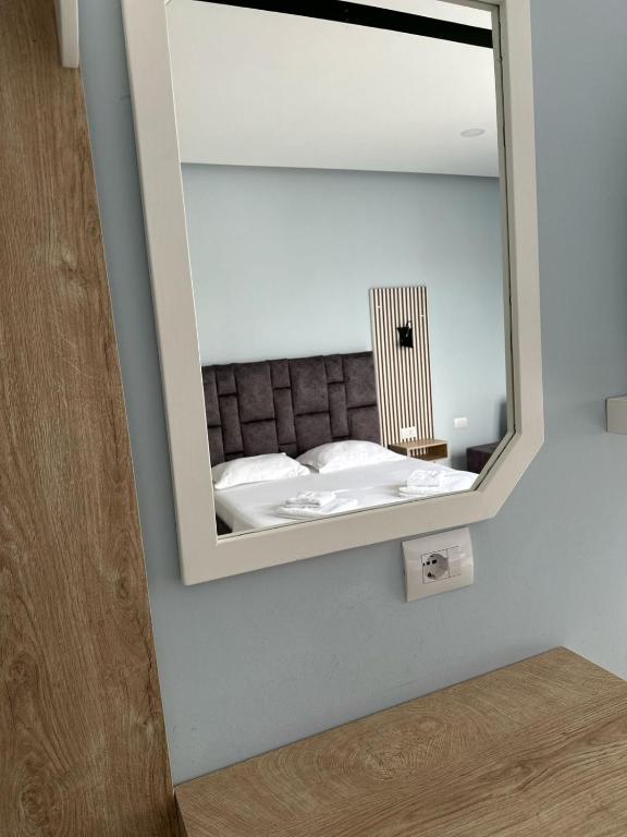 a mirror on a wall with a bed in a room at Summer Gate Hotel in Ksamil