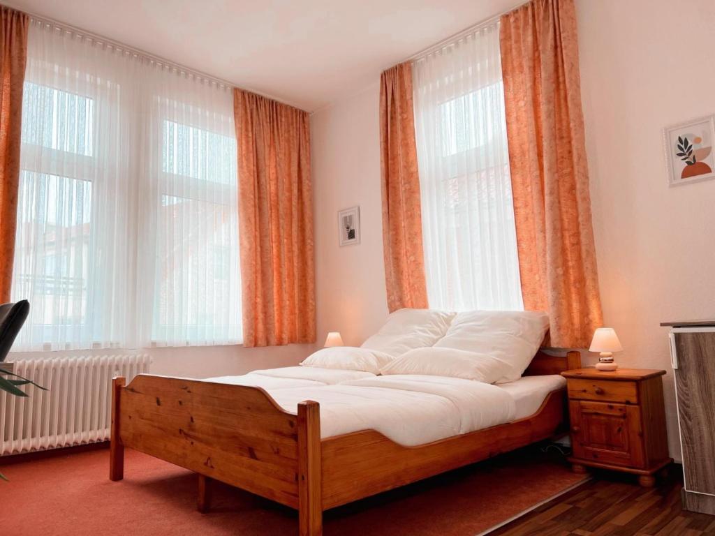 a bedroom with a bed with orange curtains and windows at Dions Rooms in Norderney