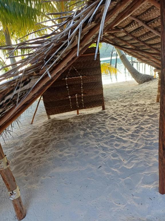 a straw hut on a beach with the ocean at Poemanahere island in Te-Fare-Arii