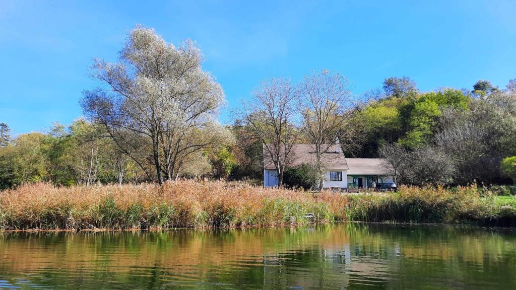 an old house sitting on the side of a lake at Kökényház vendégház in Kötcse