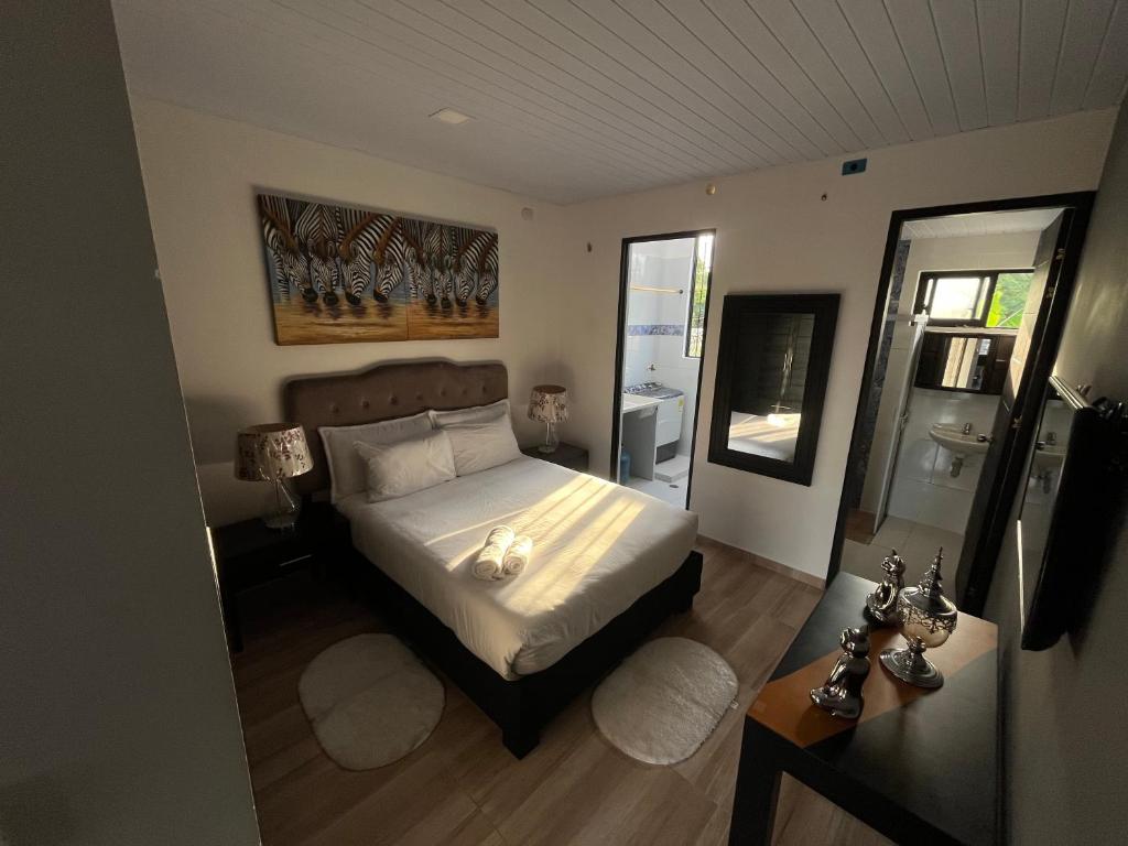 um quarto com uma cama com lençóis brancos e um espelho em Rio Aparta-Hotel 4 em Letícia