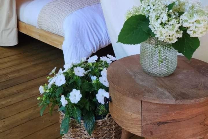a vase of flowers on a table next to a bed at The Fox Den in Delta