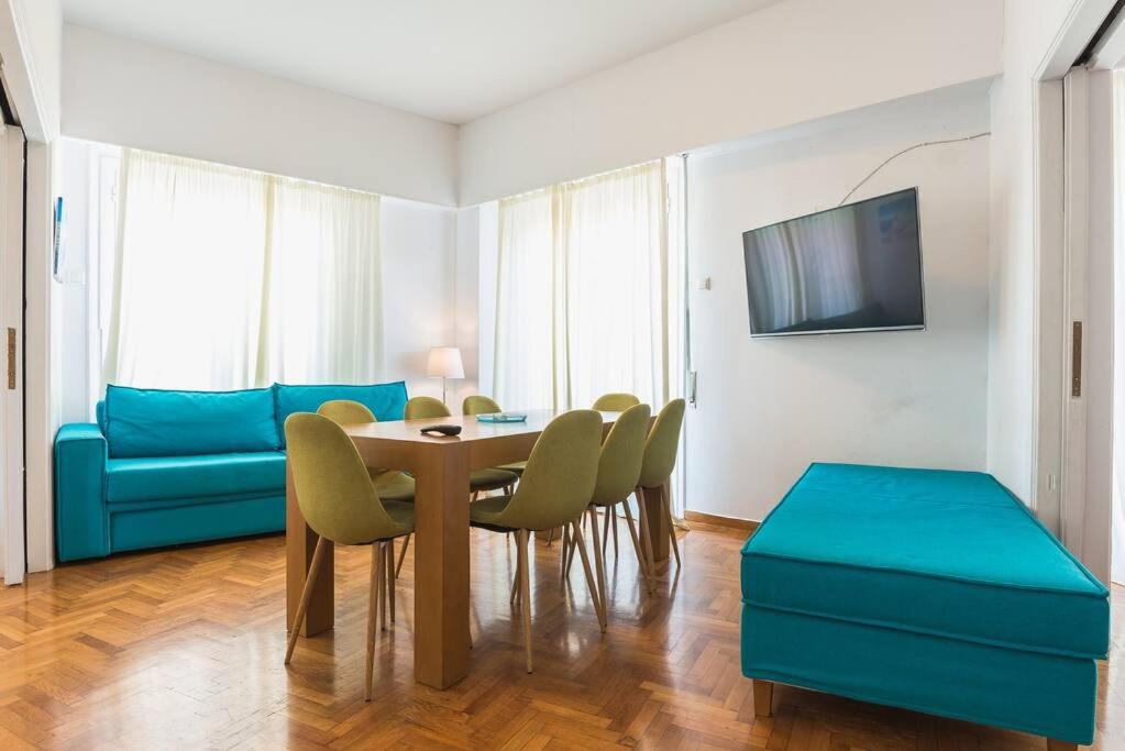 uma sala de jantar com mesa e cadeiras e um sofá azul em Athens 360 Acropolis View Apartment em Atenas
