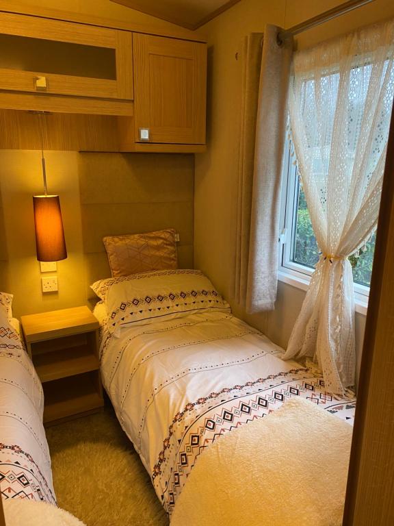 a bedroom with two beds and a window at Private luxury lodge Hafan y Mor Gwynedd North Wales LL53 6HX in Chwilog