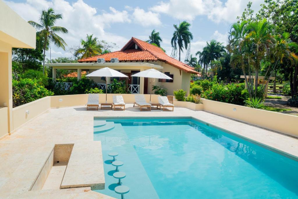 a swimming pool with two chairs and a house at Villa Diana in Las Galeras