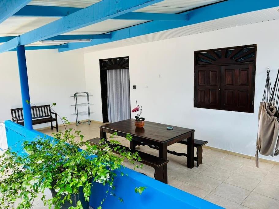 une terrasse avec une table en bois et un plafond bleu dans l'établissement Blue Home2 T3 meublé à Matoury pour 1 à 6 voyageurs., à Matoury