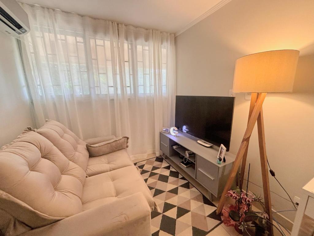 un salon avec un canapé blanc et une télévision dans l'établissement Apê Esplanada, à Brasilia