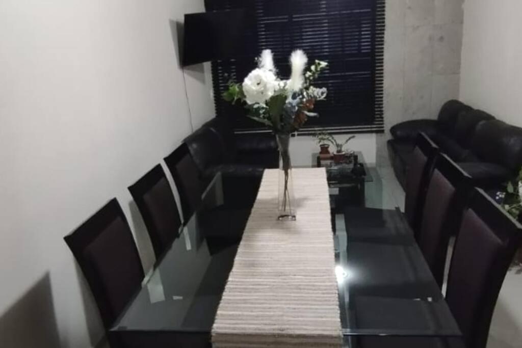 a dining room table with a vase of flowers on it at Grupo Gailla Departamento in Mexico City