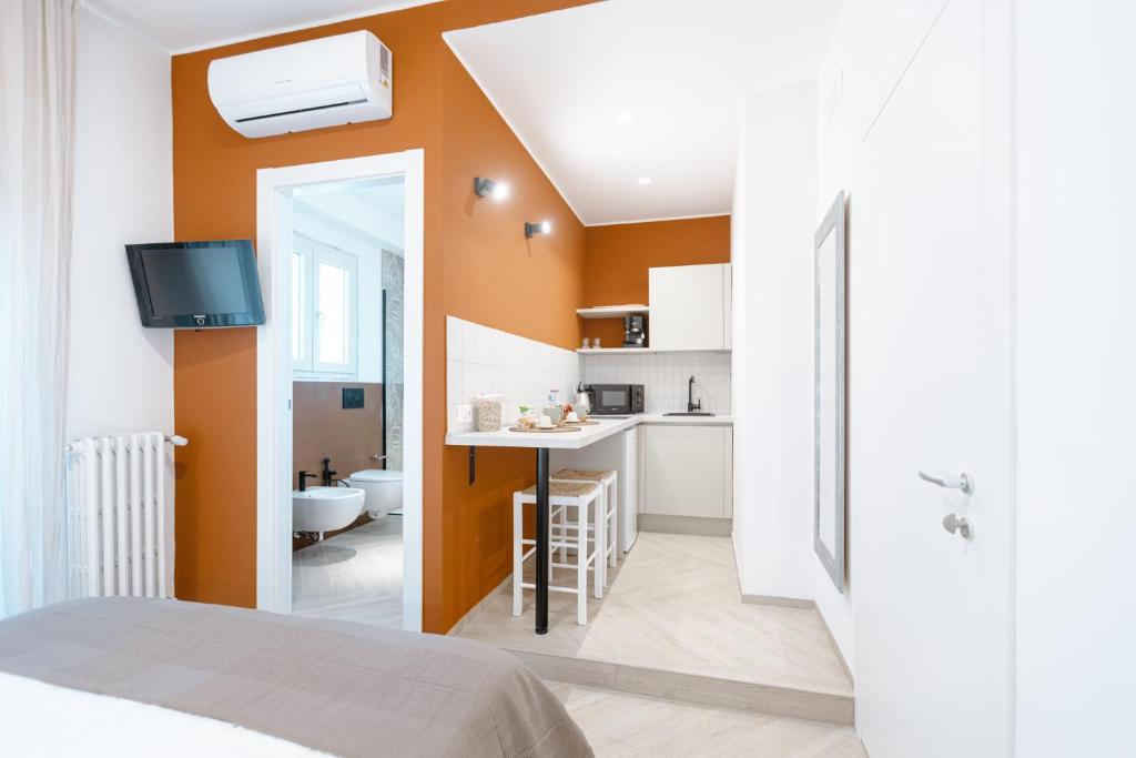 a bedroom with an orange wall and a kitchen at Porta del Salento APARTMENT in Brindisi