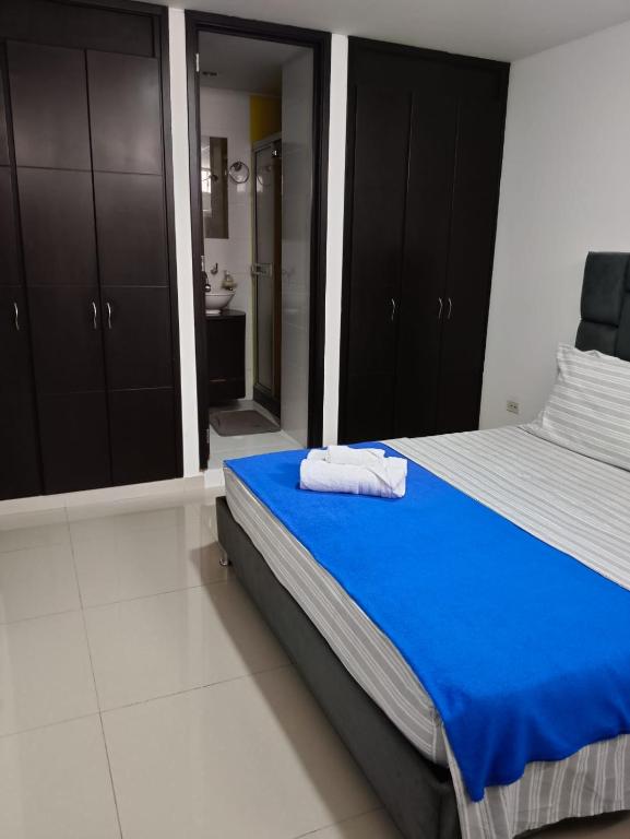 1 dormitorio con cama azul y baño en Habitación en apartamento familiar, en Armenia